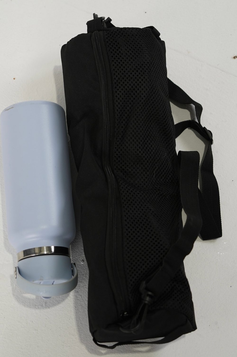 The packed Pacto in its carry bag, lying beside a water bottle of almost identical size